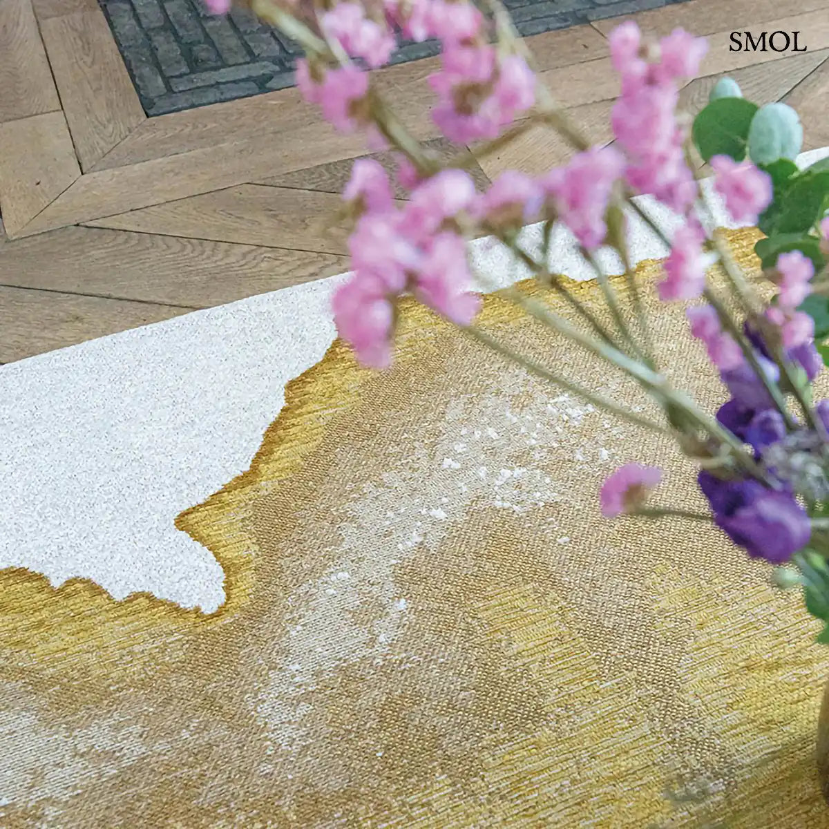 ECO RUG SUNSET szőnyeg, arany és barna színátmenettel, egyik oldalon világosabb szürkés tónusba mosódó tintafolt mintázattal, virággal