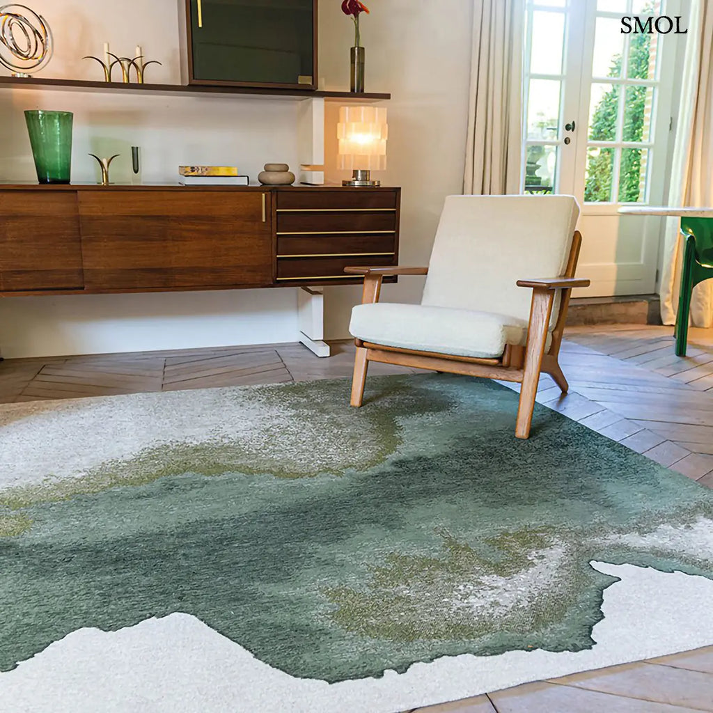 ECO RUG PALM GREEN szőnyeg, sötétzöld színátmenettel, egyik oldalon szinte fehérbe olvadó, mohaszerű tintafolt mintázattal, nappaliban, fehér fotellel