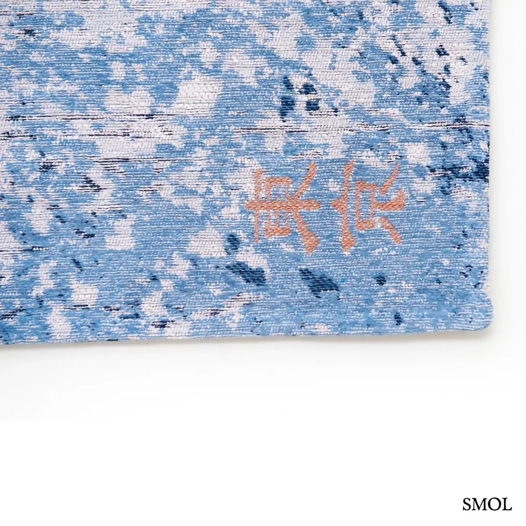 ECO RUG CONDUCTIVE BLUE városkép mintás szőnyeg kék alapon bronz és fehér akcentusokkal, absztrakt festői hatással, ázsiai írás nagyítva