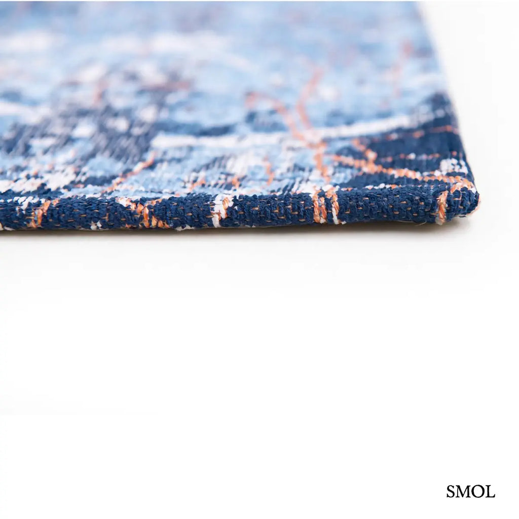 ECO RUG CONDUCTIVE BLUE városkép mintás szőnyeg kék alapon bronz és fehér akcentusokkal, absztrakt festői hatással, sarok nagyítva