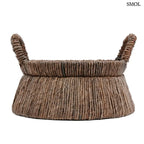 Kézzel font, sötétbarna banánlevél tárolókosár felfelé szűkülő háromszög alakú dizájnnal és masszív fogantyúkkal, oldalról