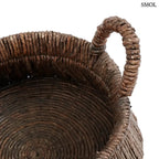 Kézzel font, sötétbarna banánlevél tárolókosár felfelé szűkülő háromszög alakú dizájnnal és masszív fogantyúkkal, felülről nagyítva