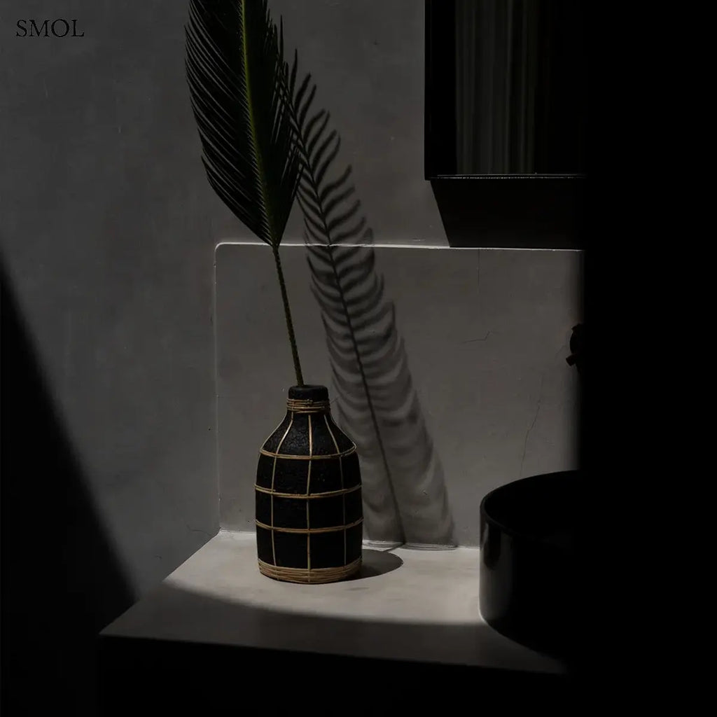 Terracotta váza fekete színben, natúr rattan fonással díszítve,  fekete levéllel