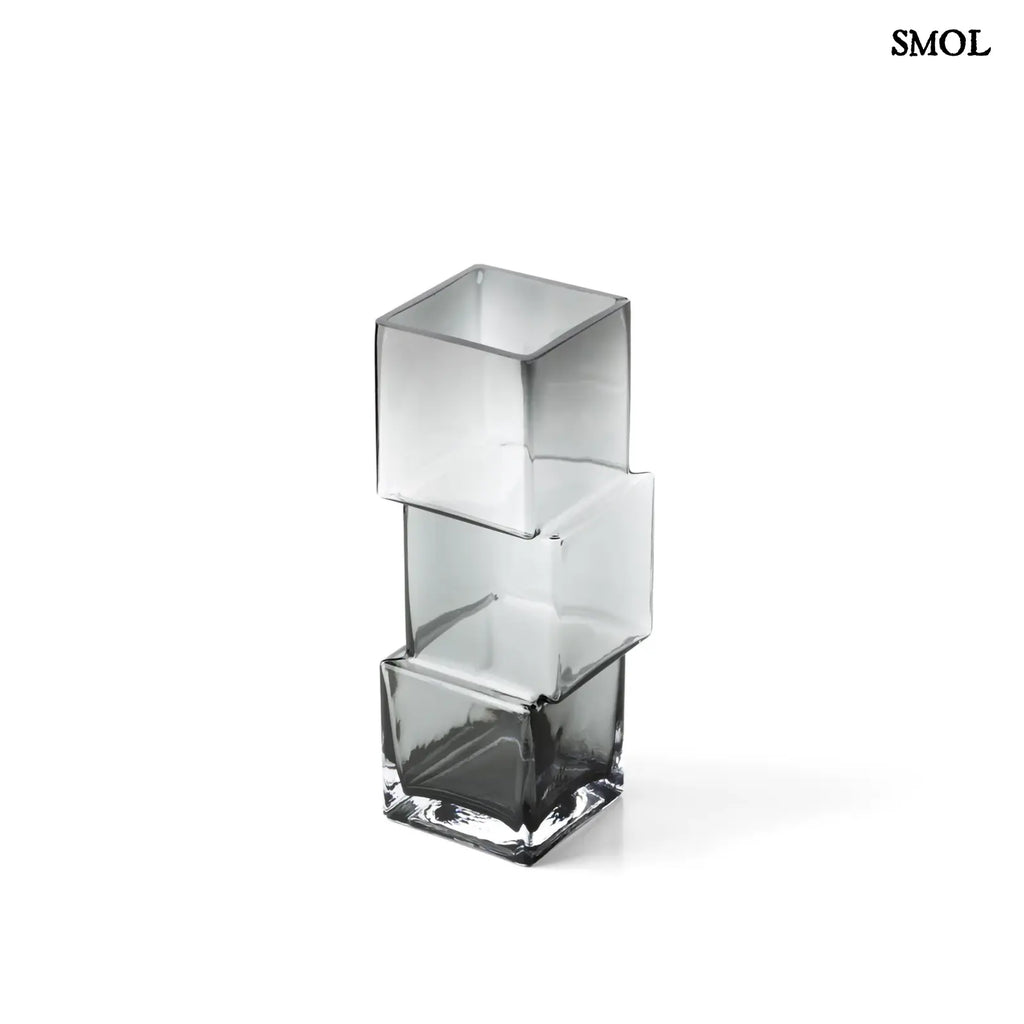 Függőlegesen elrendezett, három kocka alakú sötétszürke üveg váza, fehér háttérrel