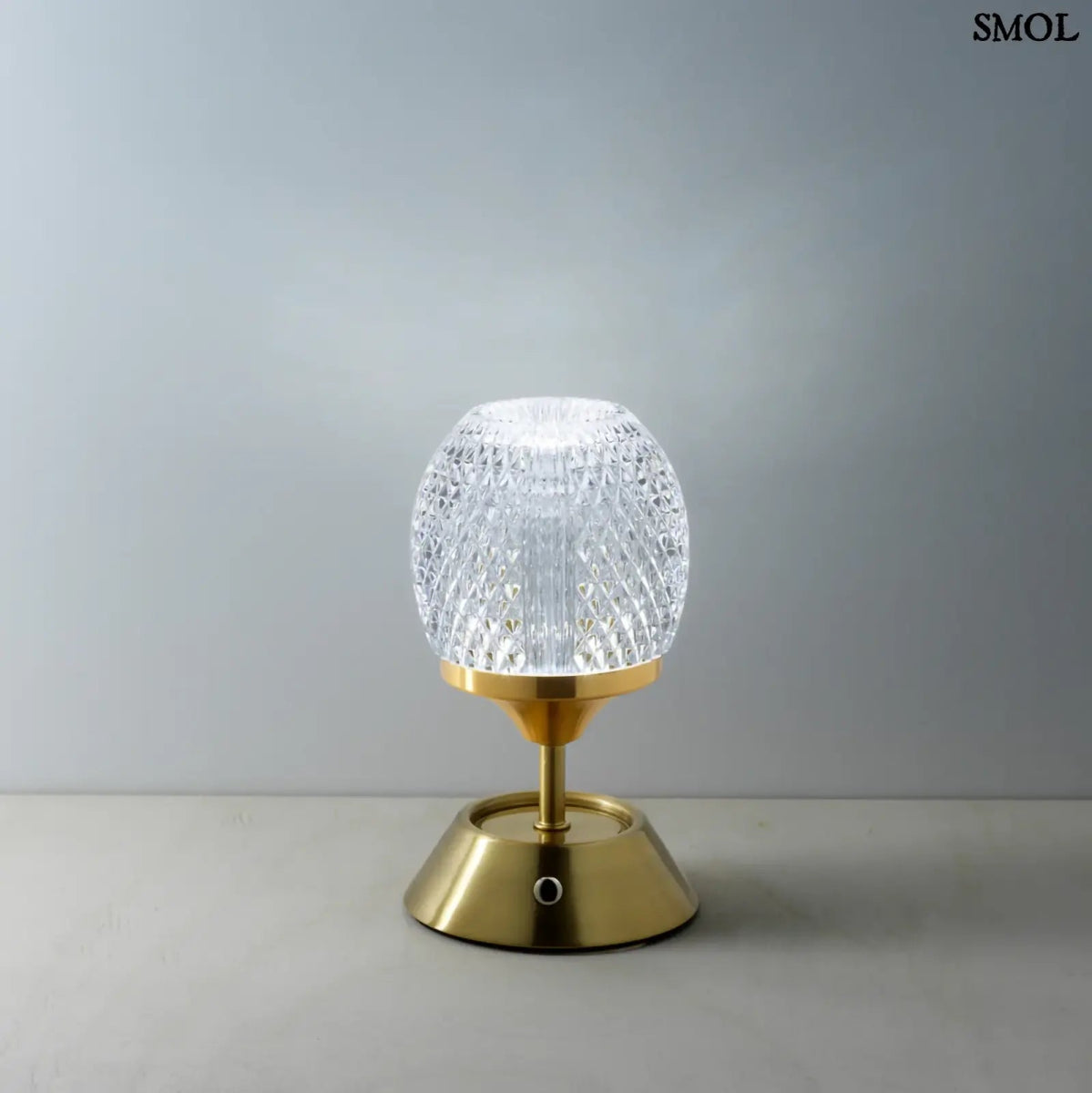 Sárgaréz talpú, kristályhatású, fazettált üveg búrával ellátott, hordozható, tölthető LED asztali lámpa szürke háttérrel