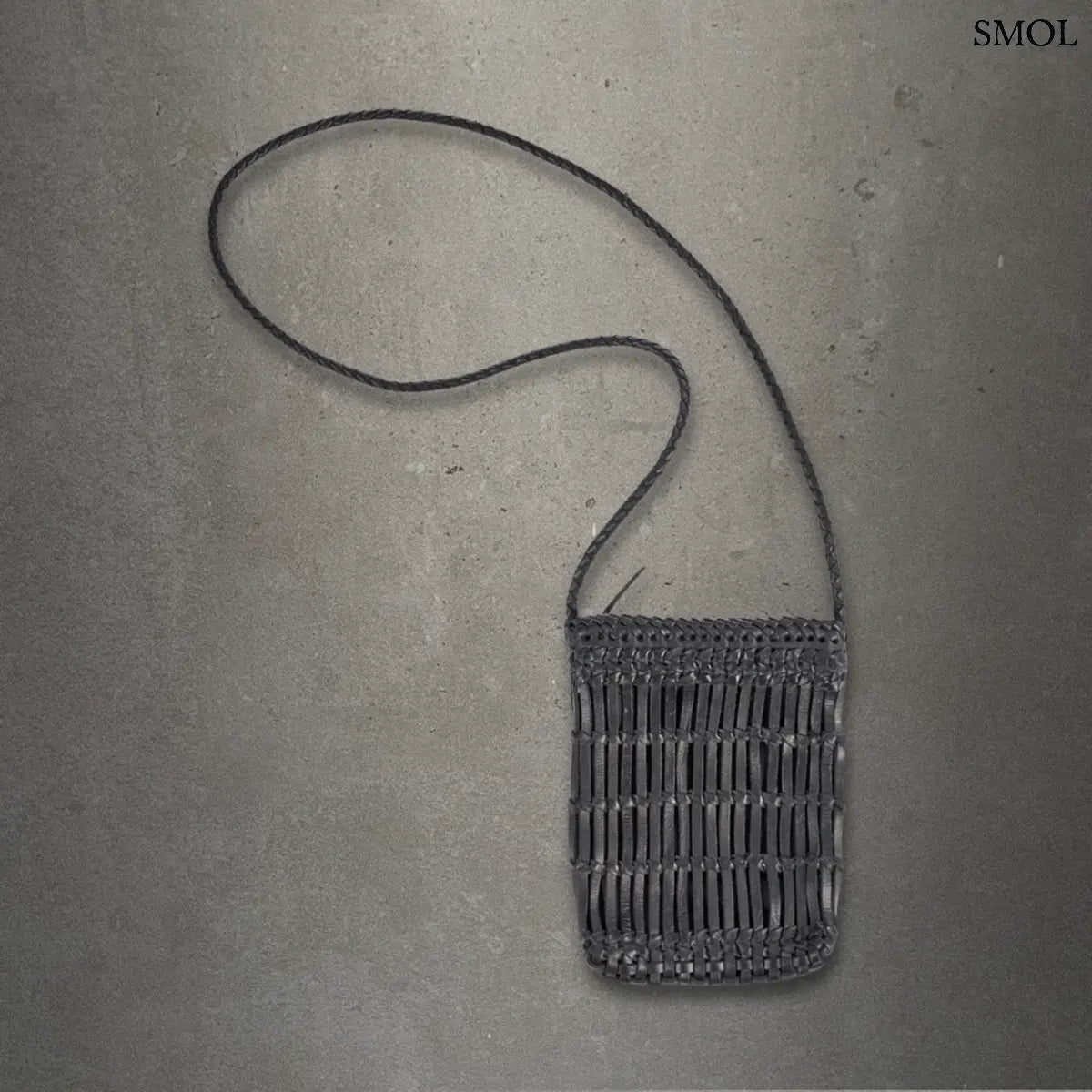 Fekete fonott bőr oldaltáska kézzel készült textúrával és hosszú vállpánttal, szürke háttérrel