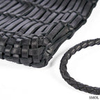 Fekete fonott bőr oldaltáska kézzel készült textúrával és hosszú vállpánttal, sarok nagyítva