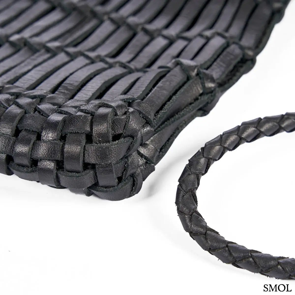 Fekete fonott bőr oldaltáska kézzel készült textúrával és hosszú vállpánttal, sarok nagyítva