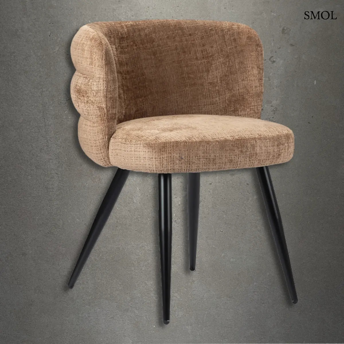 Modern, karamellbarna kárpitozott étkezőszék rétegzett háttámlával és fekete fém lábakkal, sötétszürke beton hatású háttér előtt.