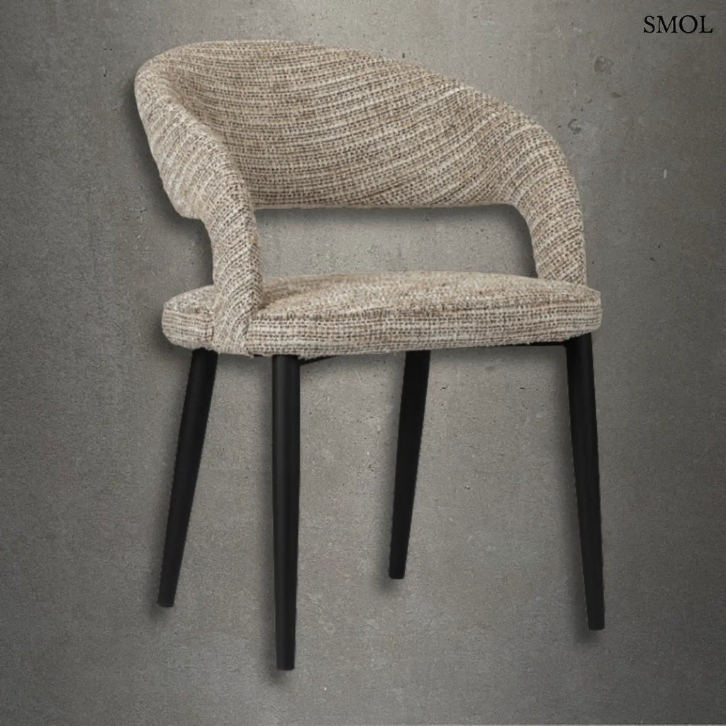 Modern, kerekített háttámlájú TUSK COCO étkezőszék bézs színű, texturált szövet kárpitozással és karcsú, fekete fém lábakkal, szürke betonhatású háttér előtt.