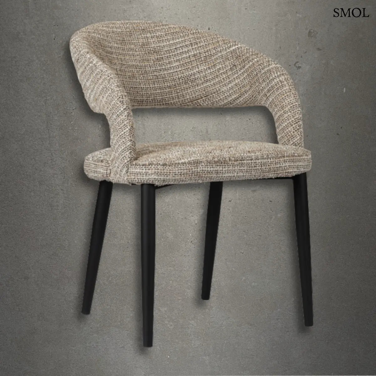 Modern, kerekített háttámlájú TUSK COCO étkezőszék bézs színű, texturált szövet kárpitozással és karcsú, fekete fém lábakkal, szürke betonhatású háttér előtt.