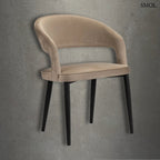 Modern, íves háttámlájú étkezőszék homokszínű bársony kárpitozással és fekete fém lábakkal, beton hatású háttér előtt.