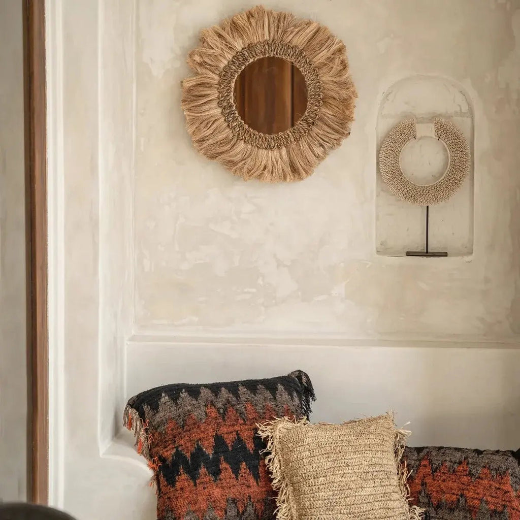 Kerek falitükör natúr fű díszítéssel és rojtos boho kerettel, nappaliban, párnákkal