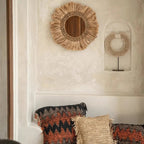 Kerek falitükör natúr fű díszítéssel és rojtos boho kerettel, nappaliban, párnákkal