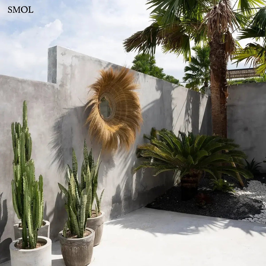 Kézzel font, kör alakú falitükör természetes szárított fűből, napsugár formájú szálakkal és mélyített üvegfelülettel, kertben