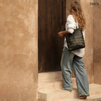 Kézzel fonott fekete bőr táska elegáns textúrával, hosszú vállpánttal és tágas kialakítással, női alakon