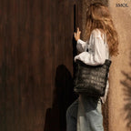 Kézzel fonott fekete bőr táska elegáns textúrával, hosszú vállpánttal és tágas kialakítással, női vállon