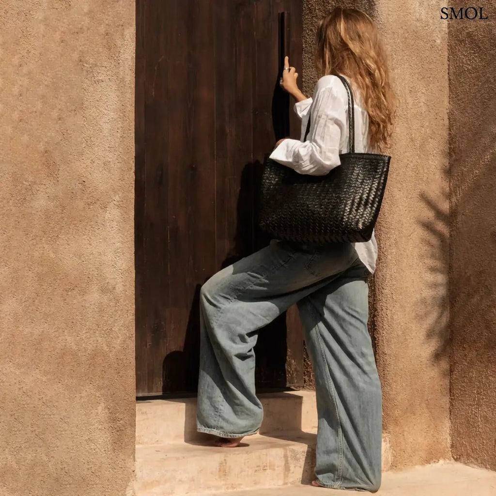 Fekete fonott bőr válltáska és óriás pakolós táska elegáns, kézzel készített textúrával, nő vállán