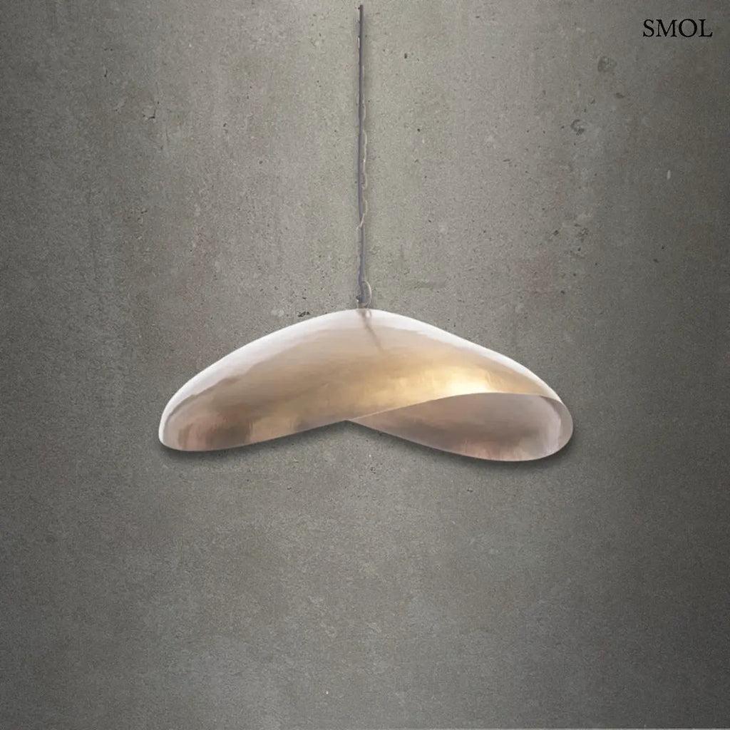 Antikolt sárgaréz függőlámpaernyő organikus ívvel és kézműves textúrával, szürke háttérrel