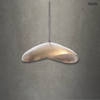 Antikolt sárgaréz függőlámpaernyő organikus ívvel és kézműves textúrával, szürke háttérrel