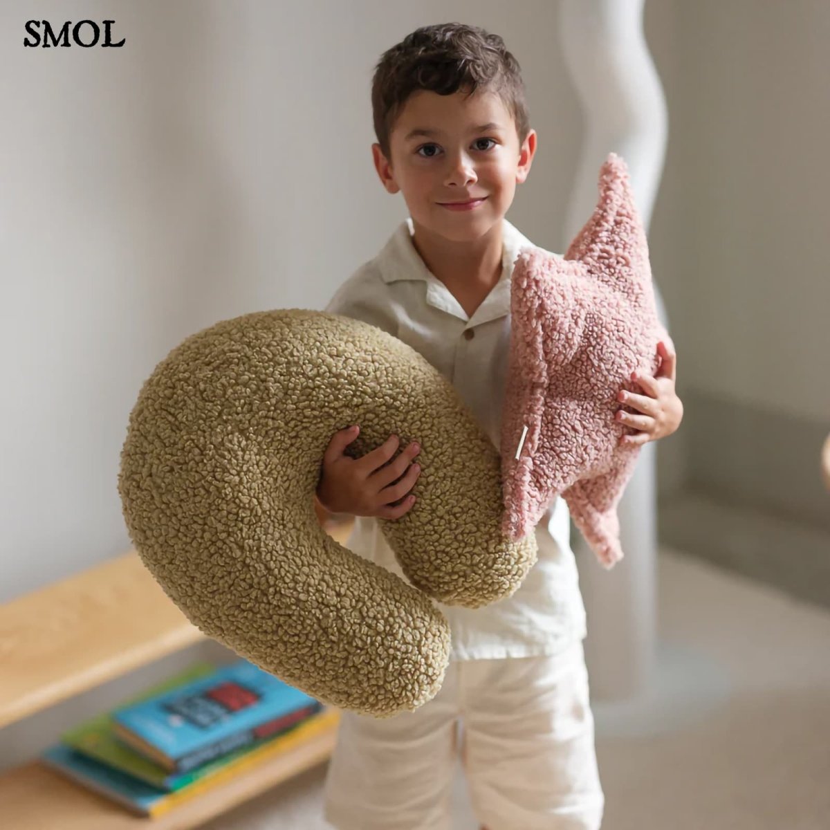 Gyerek csillagpárna | GLORI , csillag alakú, teddy anyagú gyerekpárna - SMOL - U-alakú párnával, gyerek kezében