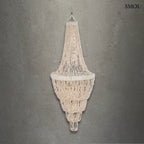 Lépcsőzetes kialakítású, fehér kagyló csillár natúr bojtos díszítéssel és fém vázzal, szürke háttérrel