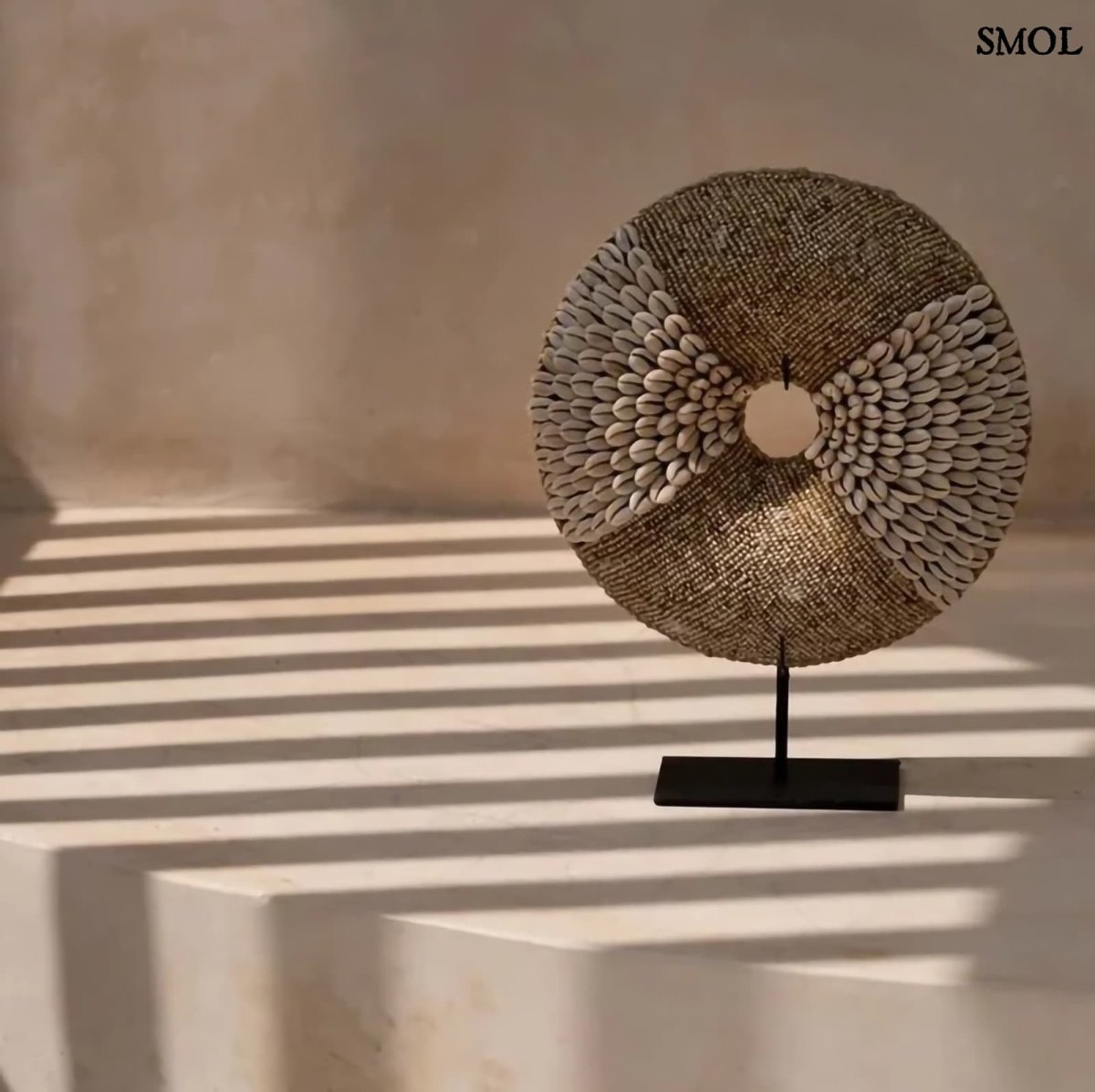 Natúr fehér kagylókból készült, kör alakú kagyló dekoráció fekete fémállvánnyal natúr háttérrel