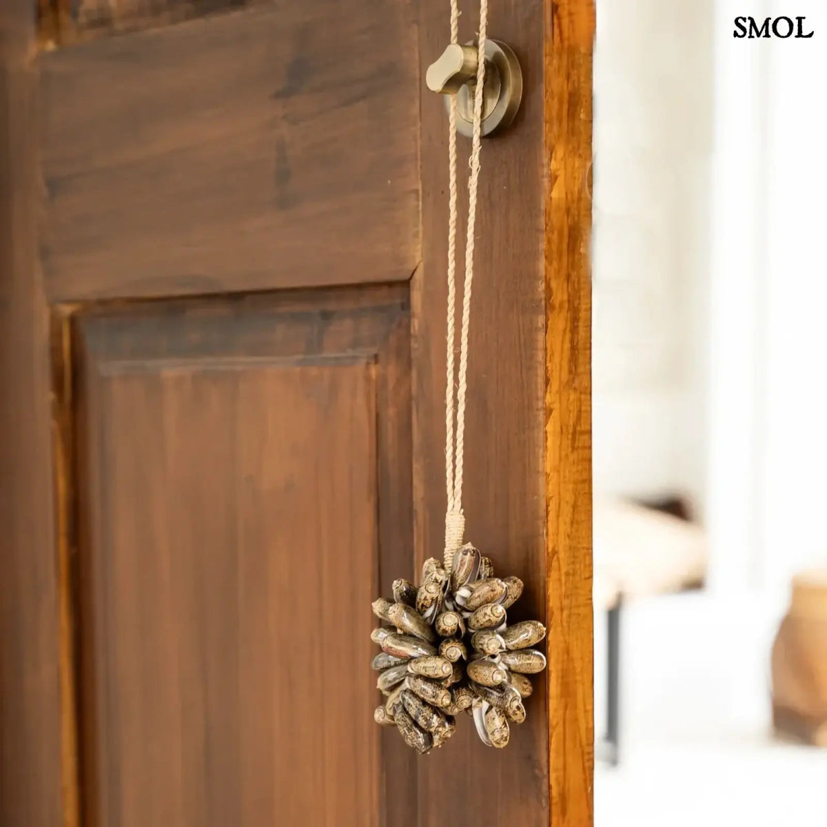 Barna kagyló függődísz, kézműves bojt formában, natúr kötélre akasztva ajtóra akasztva