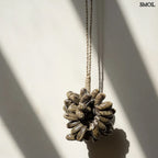 Barna kagyló függődísz, kézműves bojt formában, natúr kötélre akasztva falnál