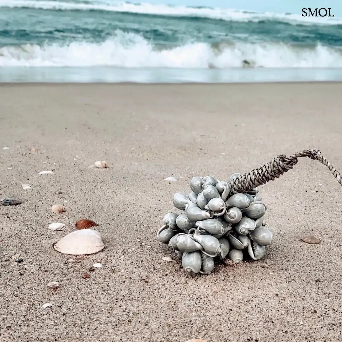 Kézzel készült, szürke színű kagyló függődísz sodrott kötéllel, tengerparton