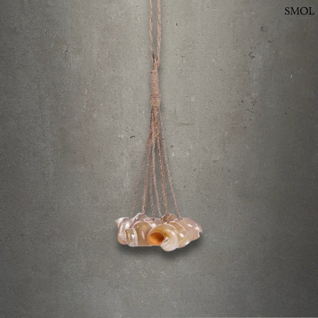 Kézzel készített kagylós dekoráció natúr kötélen függő conch kagylókkal, szürke háttérrel