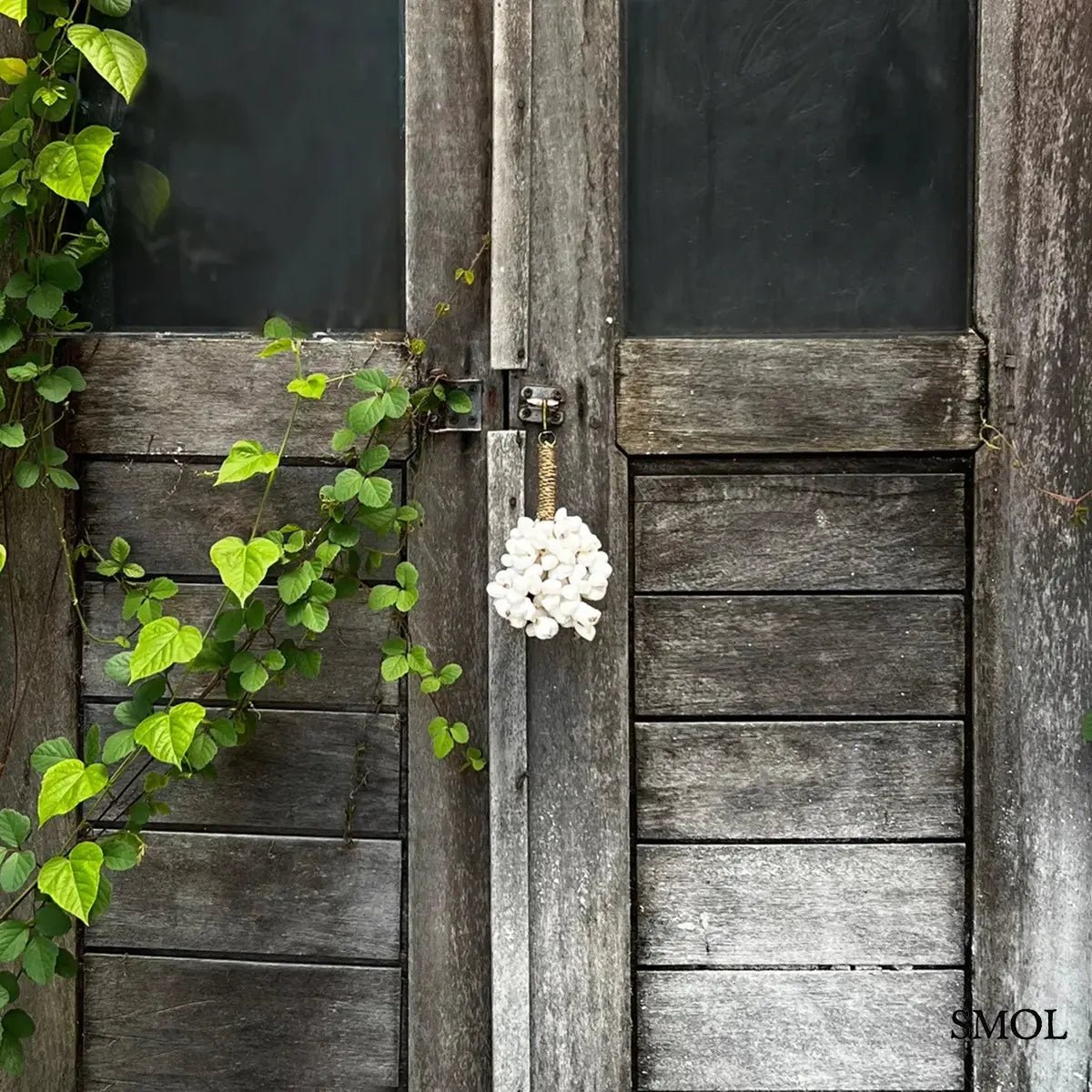 Kagylós táskadísz és kulcstartó fehér tengeri kagylókból, kézzel fonott tengerifűvel, ajtón