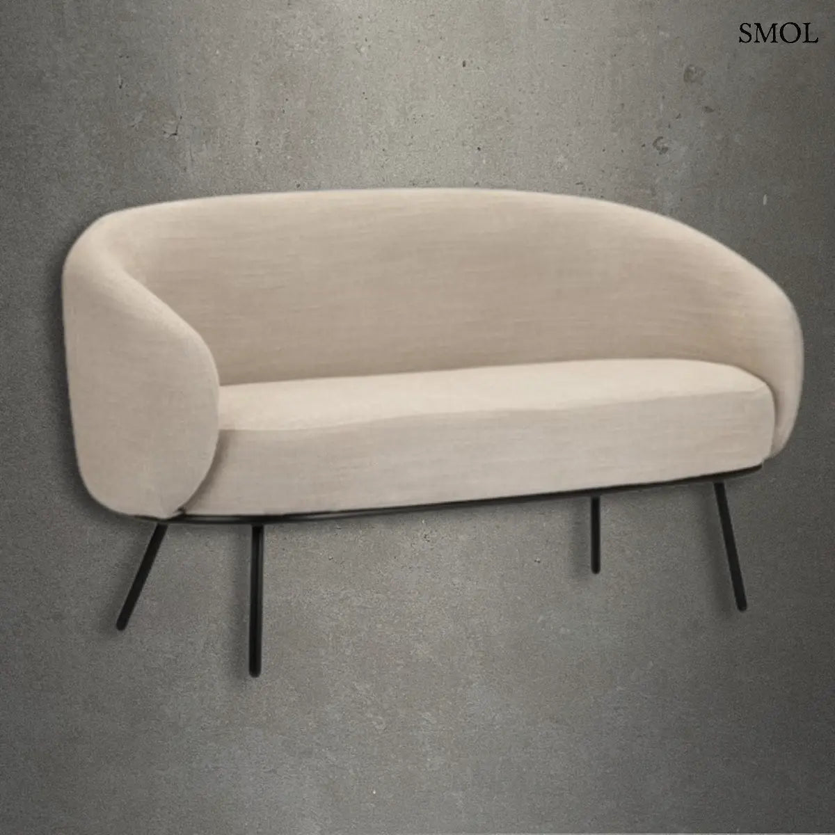 Bézs színű, modern kétszemélyes kanapé íves háttámlával és vékony fekete fém lábakkal, beton hatású háttér előtt.