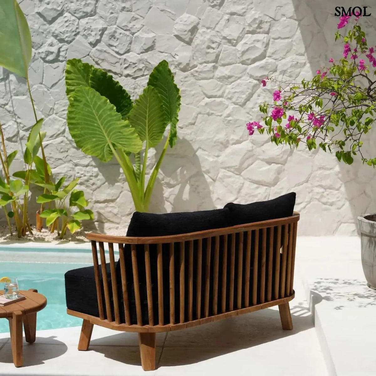 Kétszemélyes kanapé, újrahasznosított tíkfa kerettel és fekete kárpit párnákkal, teraszon, hátulról