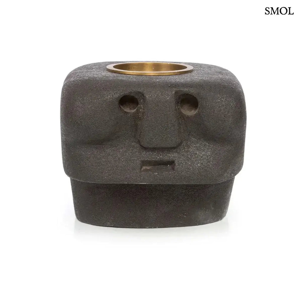 Kézzel faragott fekete kő mécsestartó misztikus arc szobor formában, sárgaréz betéttel, szemből, fehér háttérrel