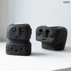 Fekete kő mécsestartó, kézzel faragott stilizált arc motívummal, Sumba-szigeti homokkőből, fekete mécsestartóval