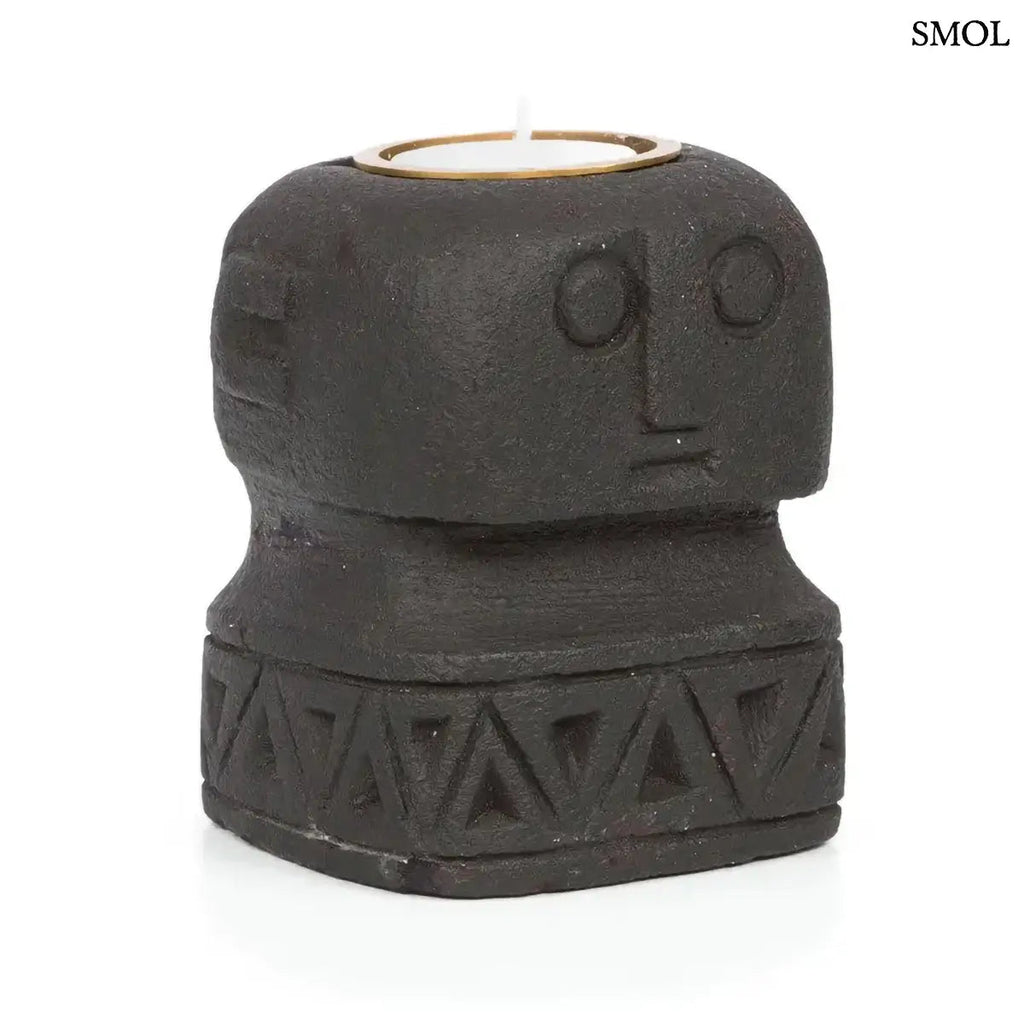 Fekete kő mécsestartó, kézzel faragott stilizált arc motívummal, Sumba-szigeti homokkőből, ferdén, fehér háttérrel