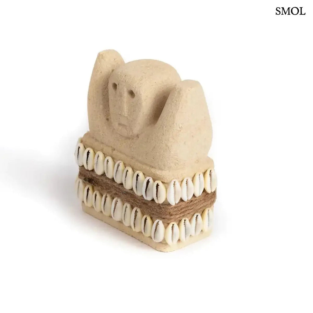 Kézzel faragott Sumba kőszobor homokkőből, fehér cowrie kagyló díszítéssel és rusztikus kötéllel, ferdén