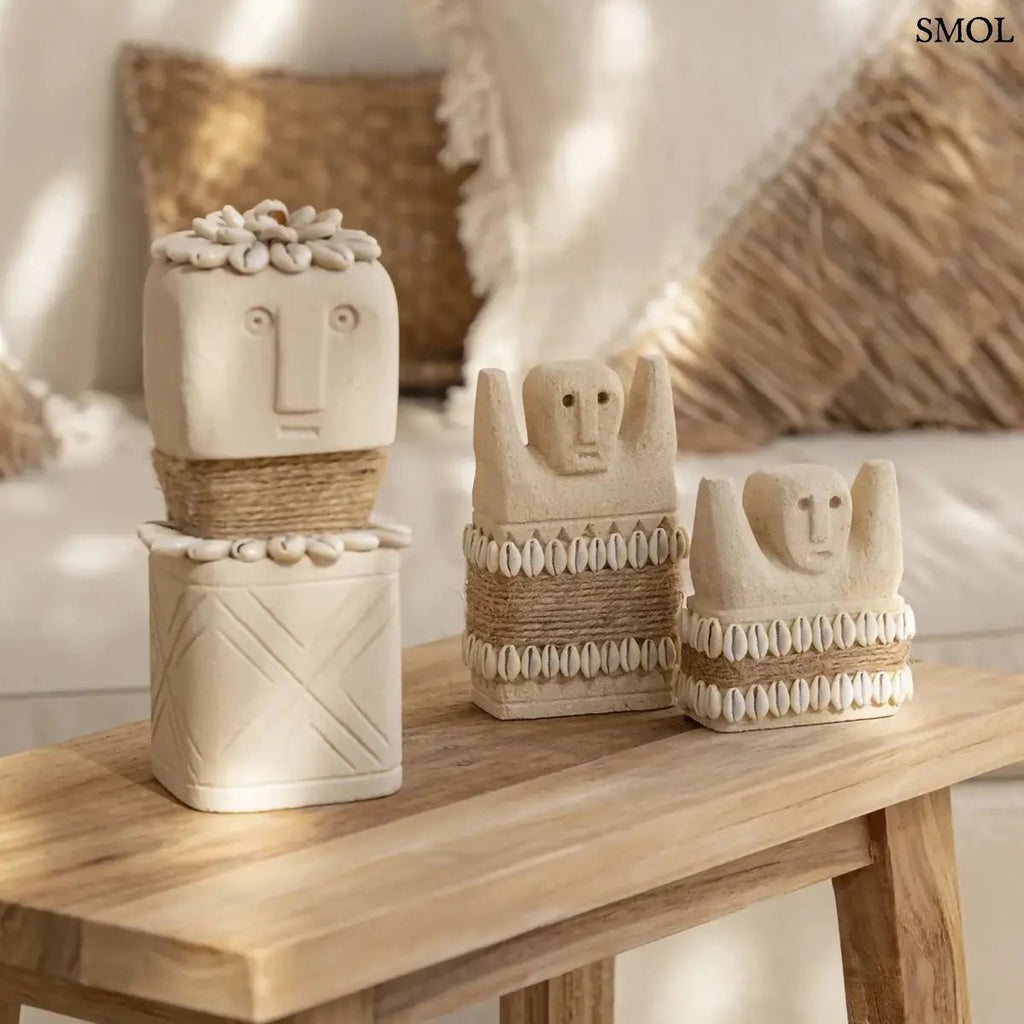 Kézzel faragott Sumba kőszobor homokkőből, fehér cowrie kagyló díszítéssel és rusztikus kötéllel, nappaliban