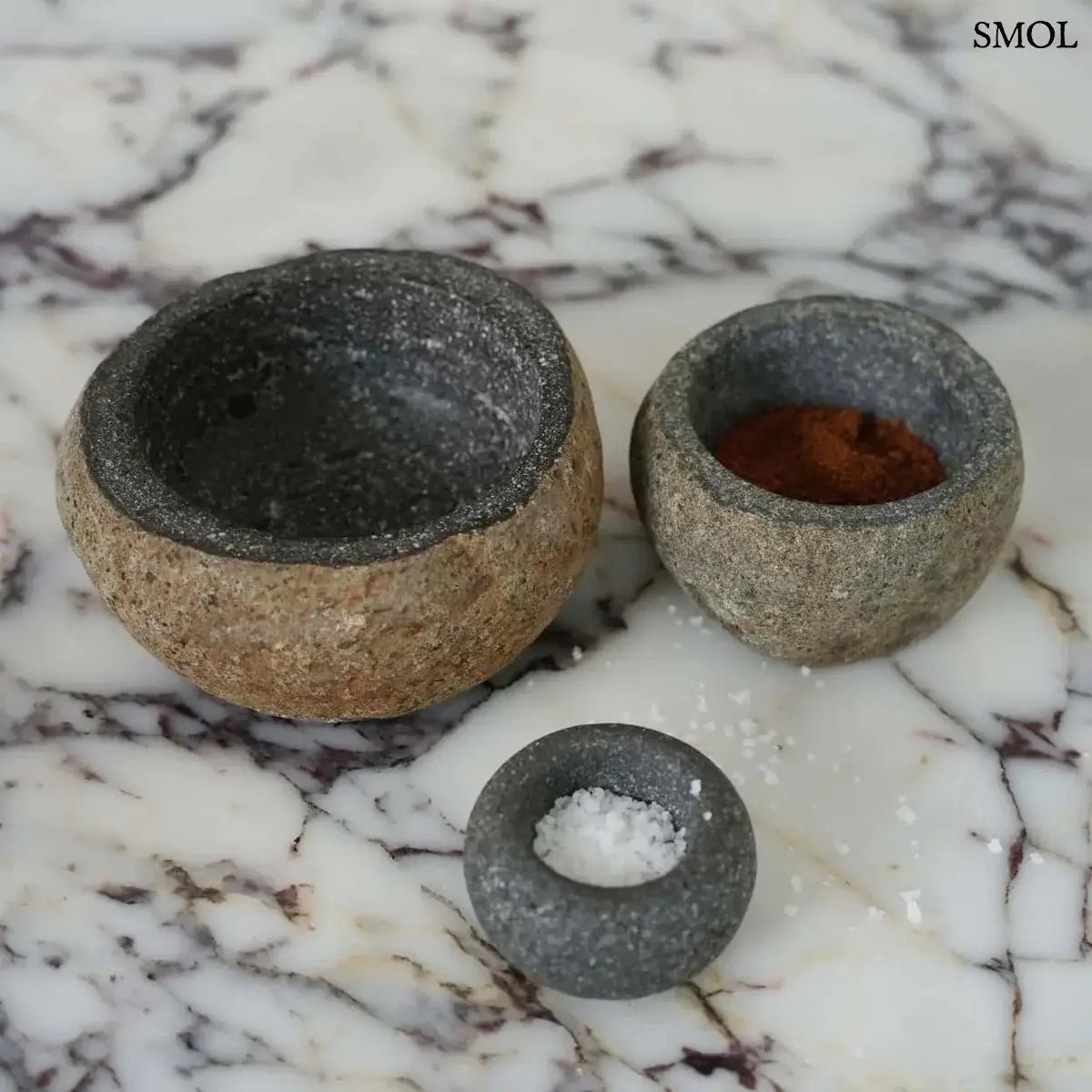 Rusztikus fekete lávakő tál kívül durva, belül csiszolt textúrával, természetes vulkanikus kőből, két méretben márványon