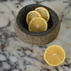 Rusztikus fekete lávakő tál kívül durva, belül csiszolt textúrával, természetes vulkanikus kőből, citrommal