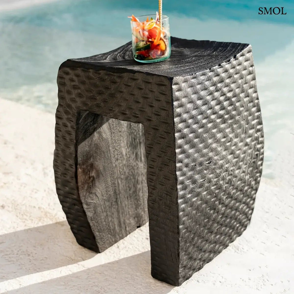 Montano fekete suar fa lerakóasztal és ülőke kézzel faragott rusztikus felülettel, medencénél koktéllal