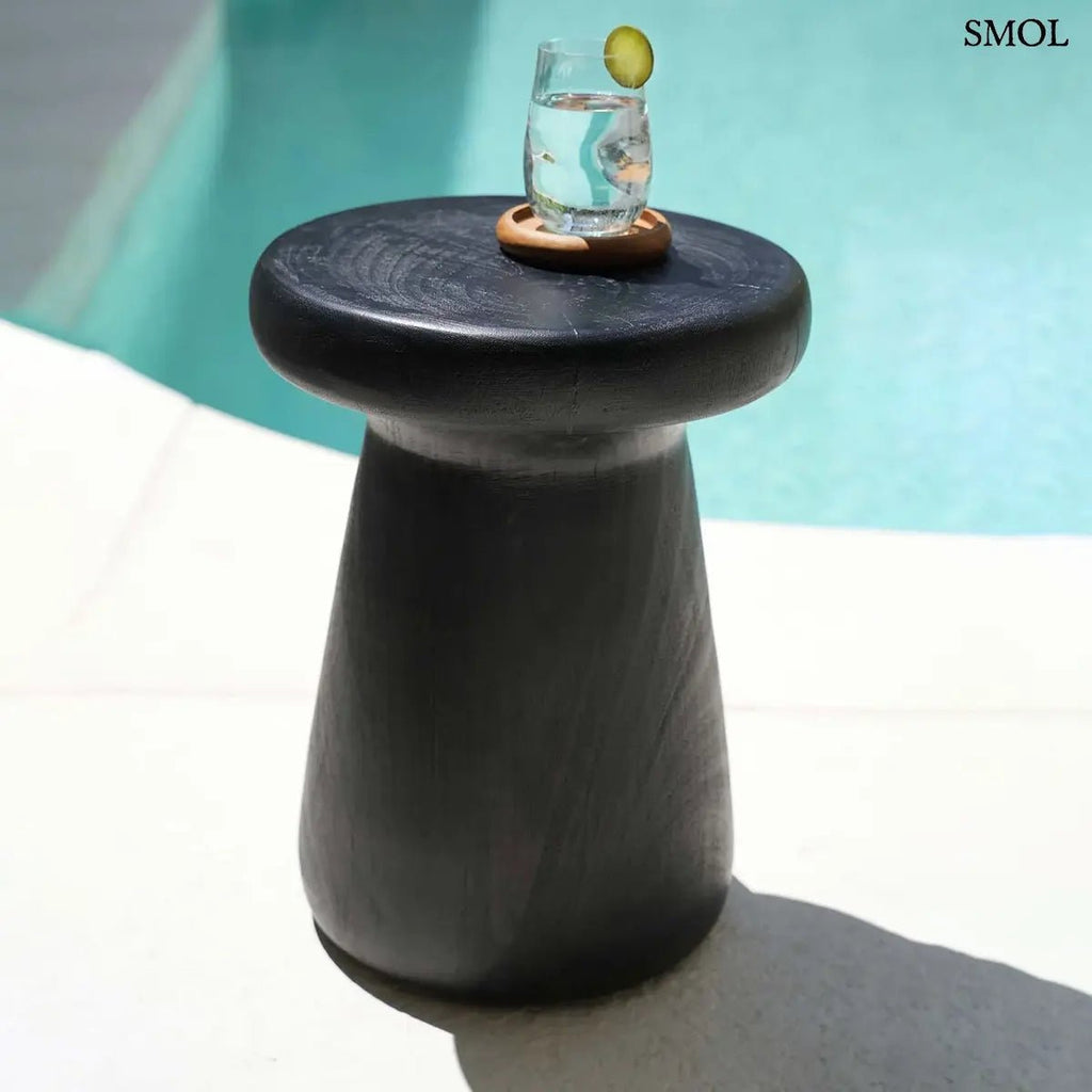 Fekete tömörfa lerakóasztal és ülőke minimalista designban, kézzel készített suar fából, vizes pohárral