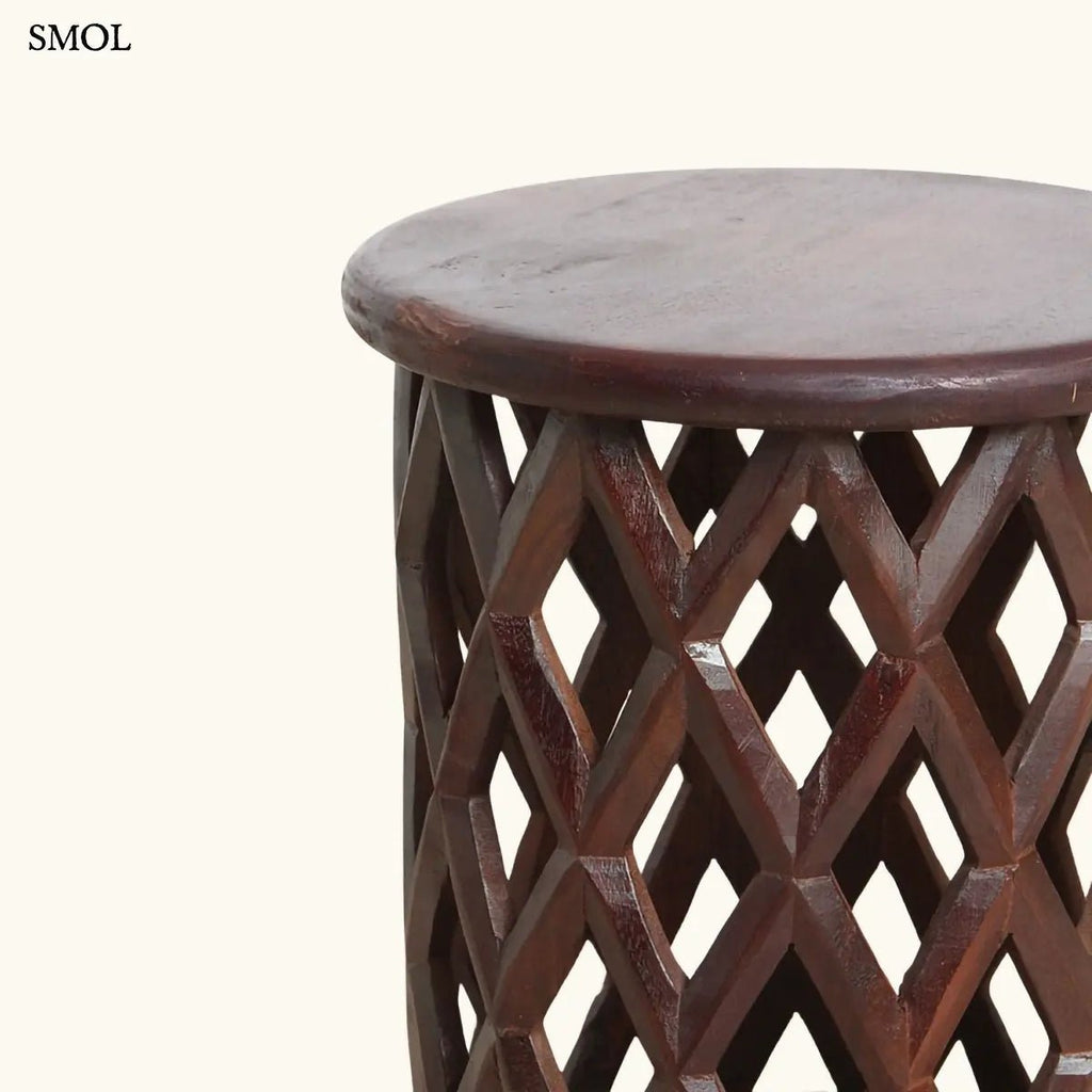 Sötét tónusú, kézzel faragott mangófa lerakóasztal és ülőke áttört rombusz mintázattal és sima, kerek fedőlappal, oldalról nagyítva