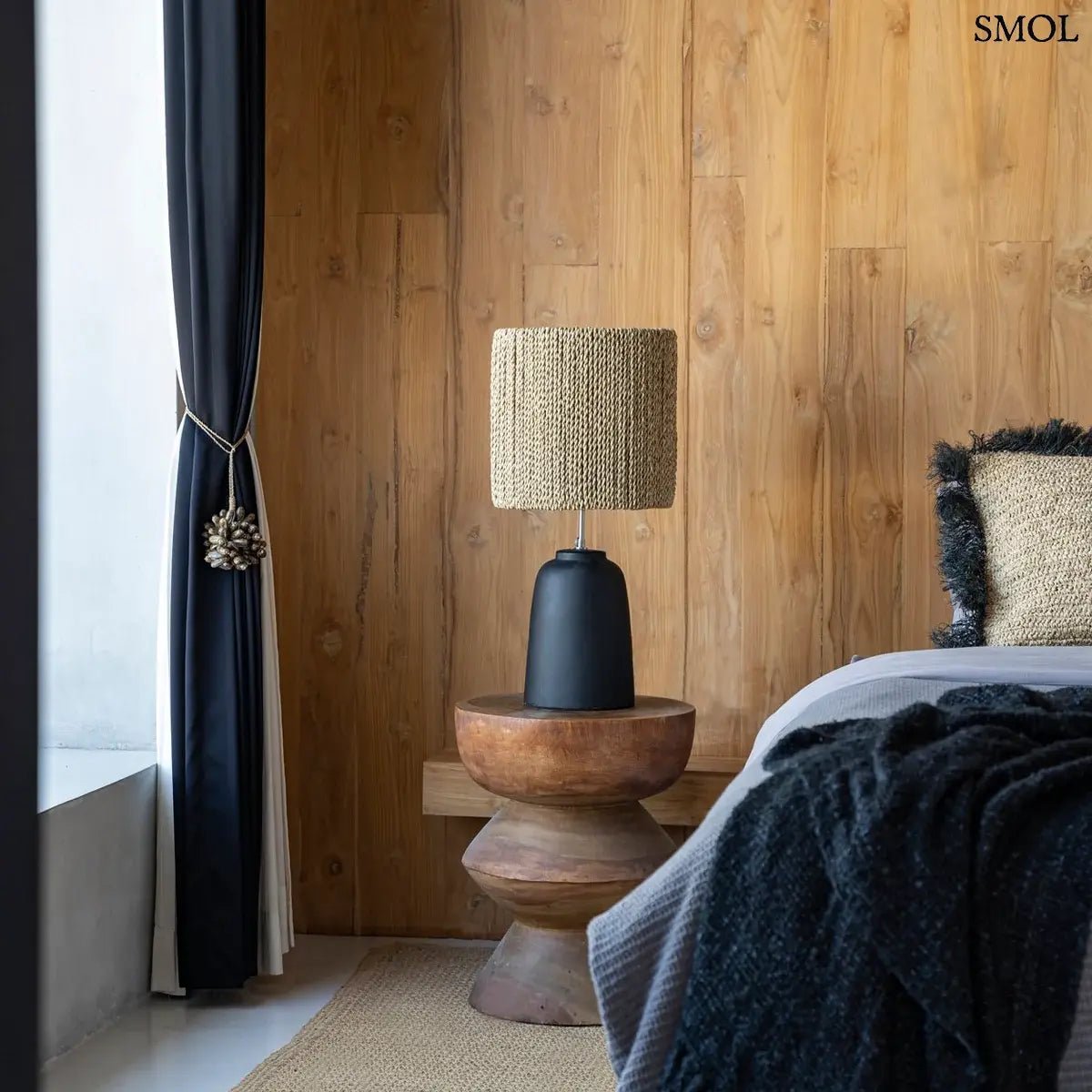 Három egymásra épülő, kerekített szelvényből álló, kézzel faragott tömör suar fa lerakóasztal és ülőke látható, természetes barna erezettel és masszív felépítéssel, éjjeliszekrényként