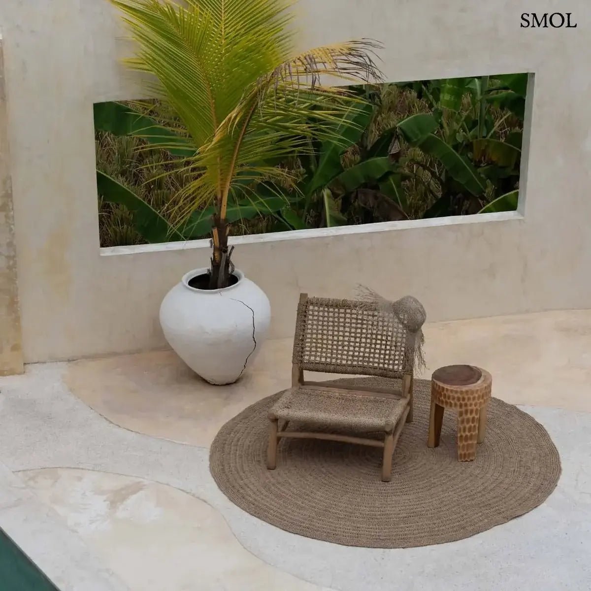 Rusztikus lerakóasztal és ülőke kézzel faragott tömör suar fából, háromlábú kivitelben és természetes fa erezettel, teraszon, fotellel, szőnyeggel