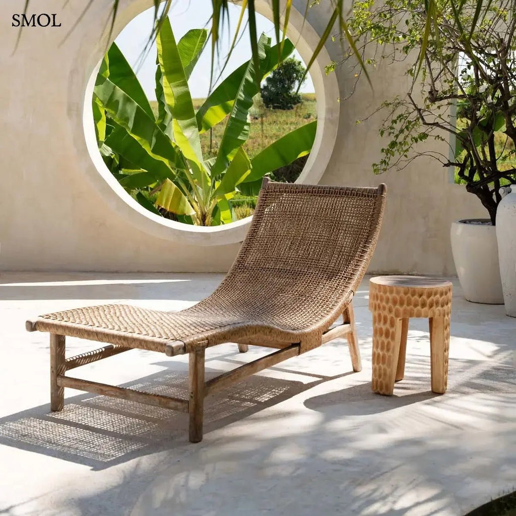 Rusztikus lerakóasztal és ülőke kézzel faragott tömör suar fából, háromlábú kivitelben és természetes fa erezettel, teraszon, nyugággyal