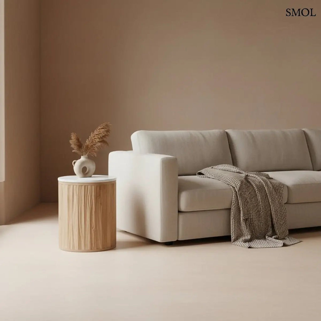 Henger alakú MALACCA lerakóasztal fehér márvány asztallappal és függőlegesen mart, natúr mangófa talppal, kanapé mellett, vázával és pléddel