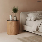 Kerek lerakóasztal fekete márvány asztallappal és függőlegesen barázdált, természetes barna mangófa talppal, hálószobában, éjjeliszekrényként