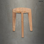 Rusztikus, kézzel faragott háromlábú teakfa lerakóasztal természetes erezettel, szürke háttérrel